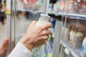 Fotobehang Hand with vegan almond milk in the refrigerated section of the supermarket © Robert Kneschke