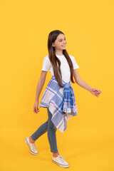 Fototapeta premium hipster cheerful child in casual clothes full length walk on yellow background