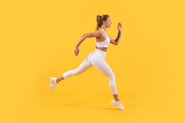 Fototapeta na wymiar energetic sport woman runner running on yellow background