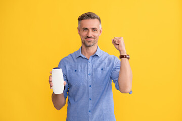successful man hold shampoo on yellow background, cosmetic