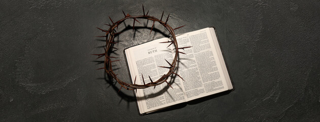 Crown of thorns with Holy Bible on dark background, top view