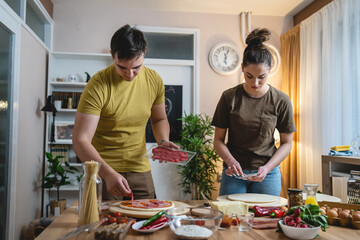 Two people young adult couple man and woman husband and wife or boyfriend and girlfriend preparing...