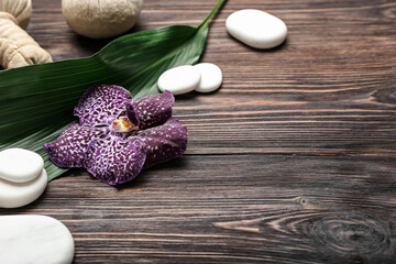 Spa composition with stones and orchid flower on wooden background