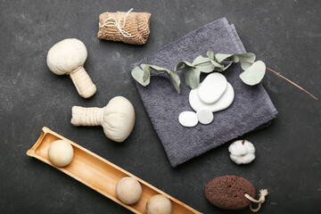 Spa composition with bathing towel, stones and herbal bags on dark background