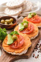 Board with crispbreads and tasty hummus on grunge background, closeup