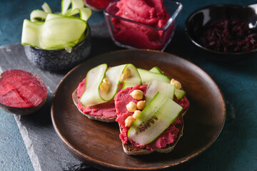 Plate with pieces of bread and tasty hummus on dark background