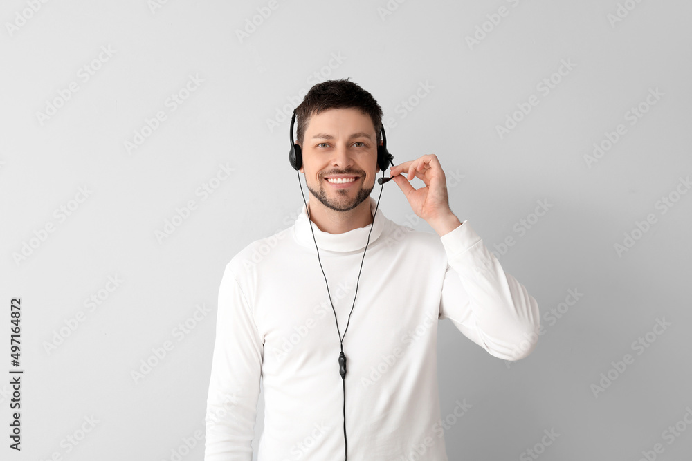 Poster smiling consultant of call center in headset on light background