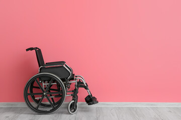 Empty wheelchair near color wall - obrazy, fototapety, plakaty