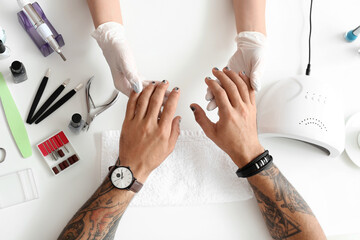 Manicure master working with male client in beauty salon, closeup