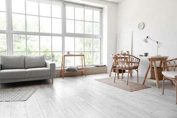 Interior of light living room with sofa, workplace and big window