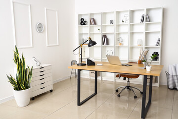 Modern workplace with laptop and lamp in interior of light office
