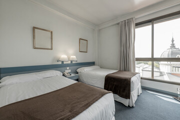 Bedroom with double beds, pale blue accents, color-matched carpet, good view out the window