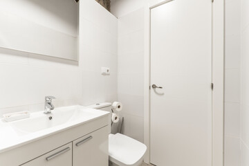 Bathroom with white furniture, white resin sink, frameless mirror and white tiles