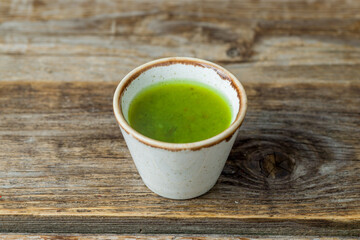 green tkemali sauce in a saucepan on old wooden table