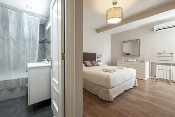 View of two rooms in a vacation rental apartment, with a toilet next to a bedroom with a double bed and a large white chest of drawers