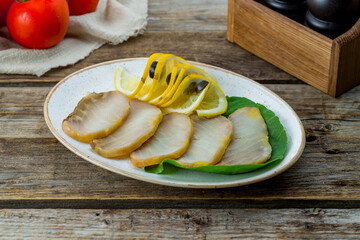 Cold smoked sliced sturgeon fillet with lemon on plate on old wooden table - obrazy, fototapety, plakaty