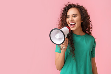 Young African-American woman shouting into megaphone on pink background