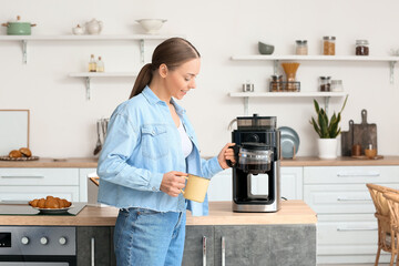 Young woman with cup and coffee machine pot in kitchen