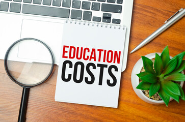 EDUCATION COSTS text on blue sticker on chart with calculator and keyboard,Business