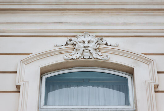 Funny white old mascaron with mustache and beard on the facade of the old house above the window. Lviv, Ukraine.