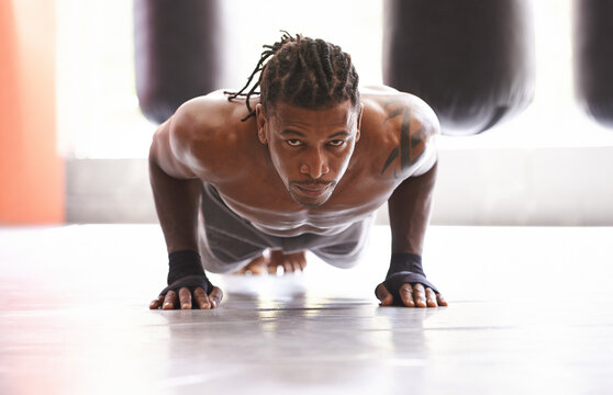 Molding his body into a fighting machine. Portrait of a young boxer doing pushups in a gym.