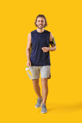 Sporty man with bottle of water on orange background