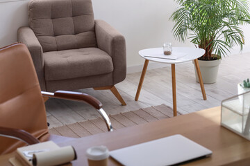 Interior of light office with coffee table and armchair