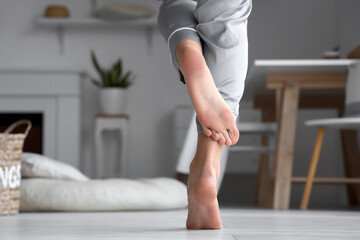 Barefoot woman in pajamas at home, closeup