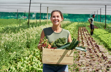 Fresh produce coming right up. Portrait of an attractive young woman carrying a crate full of...