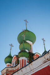 Lots of green domes of the church close-up against a bright blue sky.