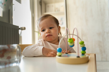 A baby girl is playing with her toys inside the house during the day