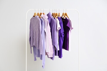 Rack with clothes in purple shades on light background