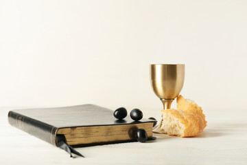 Cup of wine with Holy Bible and bread on white wooden background