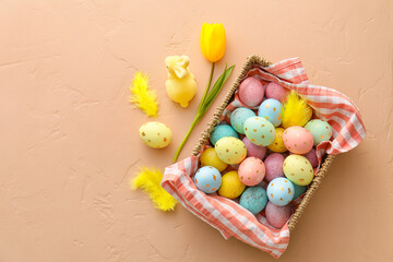 Basket with painted Easter eggs, bunny and tulip flower on beige background