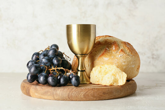 Cup of wine with grapes and bread on light background