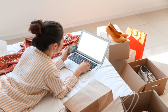 Young woman with laptop and credit card shopping online at home