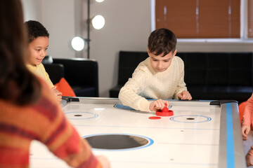 Little children playing air hockey indoors