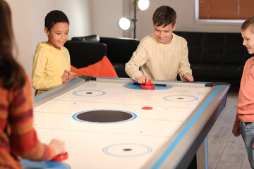 Funny children playing air hockey indoors