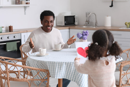 Little African-American girl greeting her dad on Father's Day in kitchen