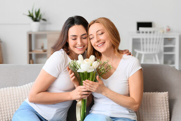 Fototapeta na wymiar Young woman and her mother with flowers on International Women's Day at home