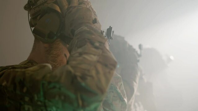Soldiers in camouflage uniform wearing helmets. Side view of group of focused men getting ready for airsoft military game in building. Battle, military, operation concept