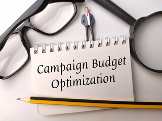 Miniature people,glasses,pencil and magnifying glass with text Campaign Budget Optimization on...