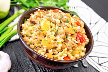 Barley porridge with minced meat in bowl on black board
