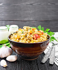 Barley porridge with minced meat in bowl on black wooden board