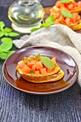 Bruschetta with tomato and basil in plate on board