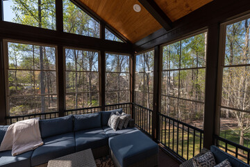 Contemporary screened porch in springtime, full of blooms trees in the background.