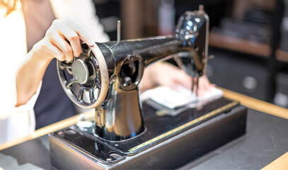 Female hand using vintage sewing machine scribbling fabric and repairing the cloth at home.