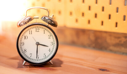 The classic black clock on the wooden backdrop shows the timing of life and time is an important concept.