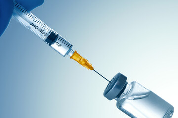 Medical syringe with a needle and a bollte with vaccine.