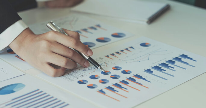 Close-up hands image, A businesswoman or female financial worker analysing financial data report, pointing pen on paperwork.